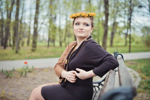 Girl sitting with a wreath of yellow flowers on her head — Stock Photo, Image