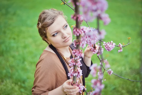 Girl near the spring branches with flowers — Stock Photo, Image