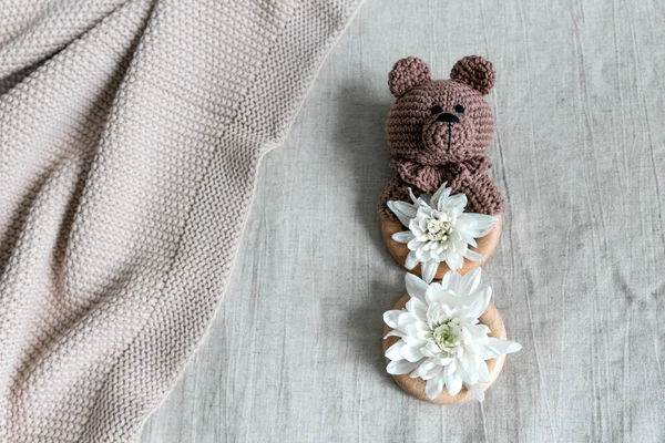 Kahverengi ayı şeklinde örülmüş bir oyuncak, açık keten arka planda duran ahşap bir ip. Kadınlar bayramının onuruna sekizinci figür olarak.. 