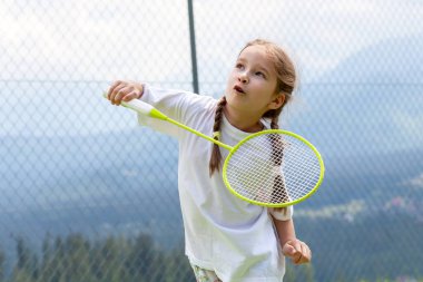 Mutlu sportif ilkokul kızı, badminton oynayan çocuk elinde raketle komik suratlar, portre, yaşam tarzı. Spor, egzersiz ve sağlıklı açık hava aktiviteleri eğlence konsepti, bir kişi