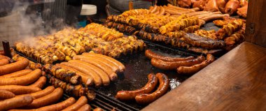 Bir sürü lezzetli et, bbq, açık hava ızgarası, sosis, shahlik, sıcak ızgaranın üstünde buhar, yüksek çözünürlük, geniş açı, panoramik, sıcak renkler. Geleneksel sokak yemekleri tezgahı, hiç kimse