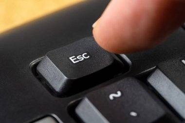 Kaçış tuşuna basan adam, basit bir siyah ofis klavyesinde, parmaklar esc tuşuna basıyor, nesne makrosu, aşırı yakın çekim, detay. Kaçmak, durmak, yazılım sembolünü bırakmak, basit bir kavram.