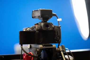 Tripod standındaki modern profesyonel aynasız kamera, bluescreen kroma anahtar stüdyo arka planı, ışıklar, canlı yayın kaydı, yayın, medya yayın konsepti, hiç kimse