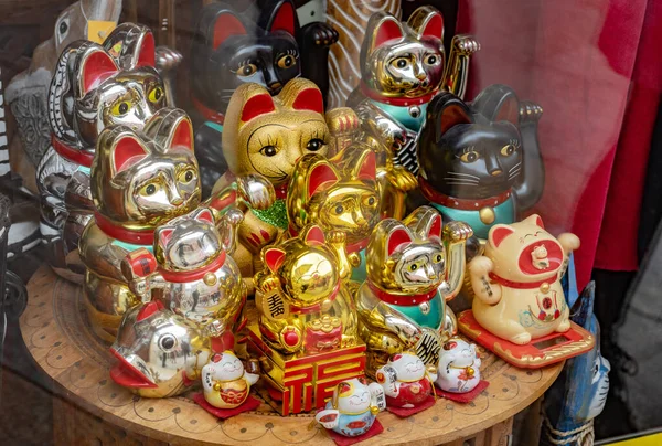 召唤猫 多个传统的日本壁虎猫在商店橱窗中招揽猫的移动爪子雕像 一组物品 陈列在商店产品上的旅游纪念品 — 图库照片