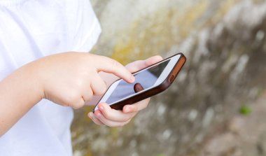 Anonim okul kızı, cep telefonunu kullanan çocuk, akıllı telefon, ekranı dinleyen, el parmağı detayı, kapalı çekim, açık hava çekimi, çocuklar ve mobil uygulamalar, basit teknoloji kavramı, bir kişi