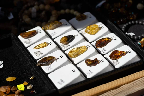 Amber jewelry on sale, baltic amber pendants, group of objects, detail, extreme closeup, nobody. Shiny natural amber beauty accessories set, polished decorative amber products collection up close