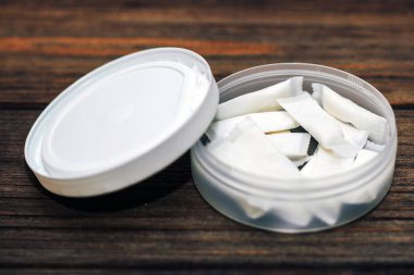 Ahşap arka planda nikotin kesesi olan Snus kutusu.