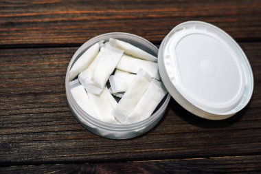 Ahşap arka planda nikotin kesesi olan Snus kutusu.