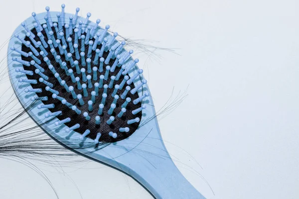 Wooden comb with fallen hair on it and scissors.