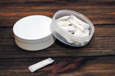 Ahşap arka planda nikotin kesesi olan Snus kutusu.