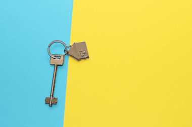 Evin anahtarı, karton mavi arka planda ev şeklinde bir anahtarlık, Ukrayna bayrağının renkleri..