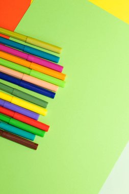 Çok renkli karton kağıdın arka planında keçeli kalemler var..
