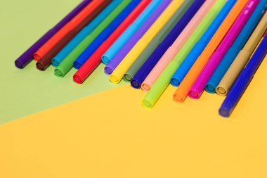 Çok renkli karton kağıdın arka planında keçeli kalemler var..