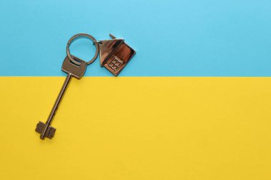 Evin anahtarı, karton mavi arka planda ev şeklinde bir anahtarlık, Ukrayna bayrağının renkleri..