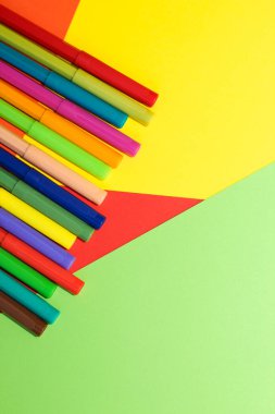 Çok renkli karton kağıdın arka planında keçeli kalemler var..