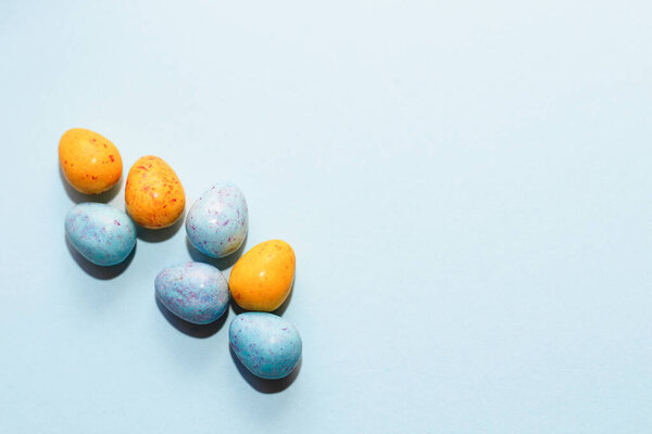 Цветные голубой и желтый шоколад пасхальные яйца конфеты на бумажном фоне.