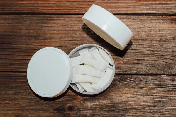 Ahşap arka planda nikotin kesesi olan Snus kutusu.