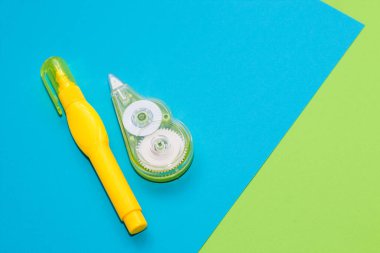 Çok renkli karton kağıdın arkaplanındaki sarı kırtasiye düzelticisi.