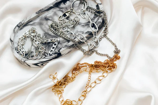 Alçıtaşı mermer süsleme standı ve ipek standın arka planında gümüş ve altın mücevherler.