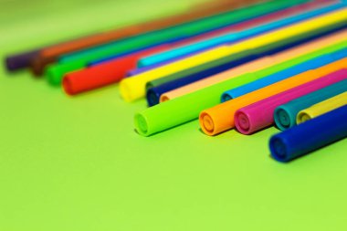 Çok renkli karton kağıdın arka planında keçeli kalemler var..