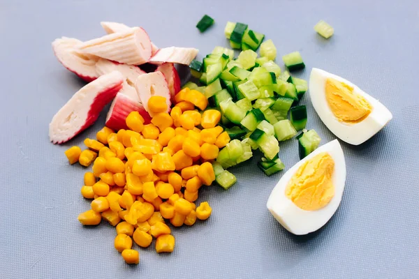 Salata için dilimlenmiş yengeç çubukları, doğranmış salatalık ve yumurta..