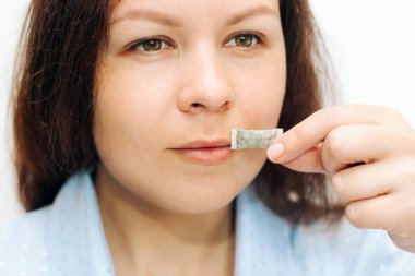 Kız elinde bir yastık, snbcha nikotin kesesi tutuyor..