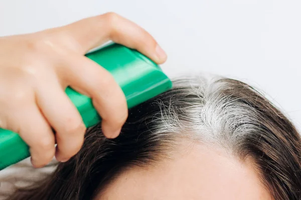 Koyu tüylü saç köklerine kuru şampuan sıkan bir kız..