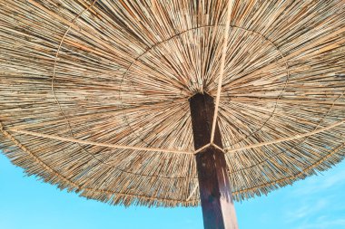 Mavi gökyüzünün arka planında saman plaj şemsiyeleri, tatil konsepti.