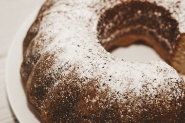 The baked dessert is a round cupcake sprinkled with powder.