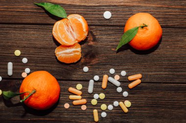 Tangerines on the background of a wooden table with vitamins and pills.