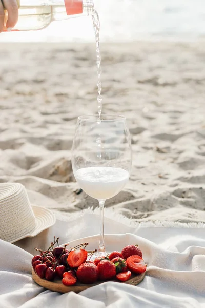 Güneş koruması için ağzına kadar dolgulu saman plaj şapkası bir tabak meyve ve şarapla.