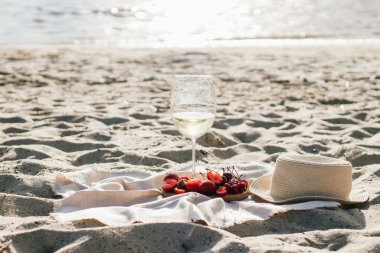 Plajda bir piknikte çilek ve kirazlı meyve tepsisiyle şampanya..