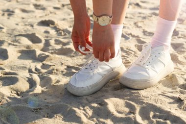Kumda etekli, şık spor ayakkabılı bir kızın bacakları. Görüntü yürüyüş için alınır..