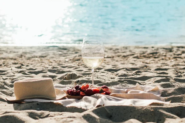 Champagne with fruit tray with strawberries and cherries on a picnic on the beach.