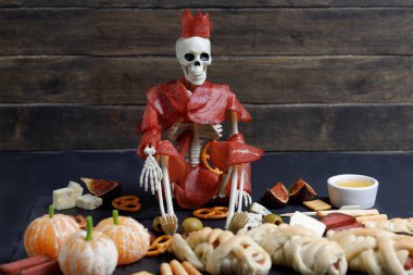 İskeletli Cadılar Bayramı Yemeği ve siyah arka planda abur cubur tabağı olan mumya..