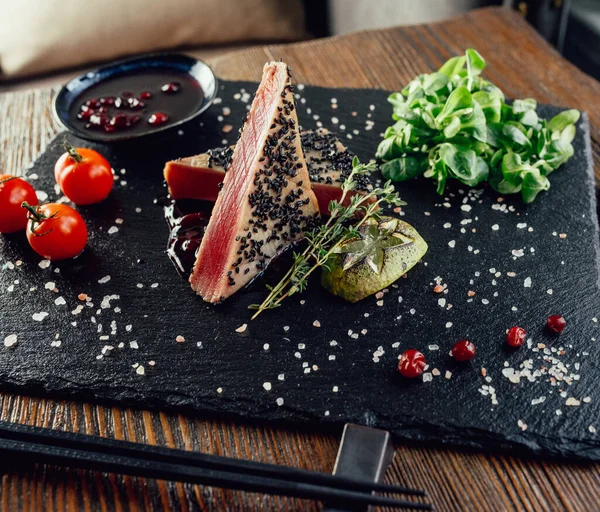 Keten tohumlu ton balığı, domates, otlar, seramik siyah tabakta çilek sosu.