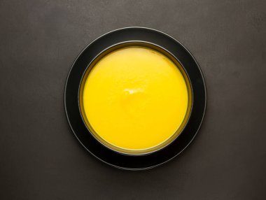 Kabak çorbasının en üst görüntüsü siyah tabakta, siyah yüzey üzerinde.