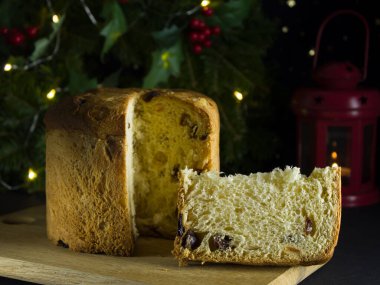 Tahta bir tahtanın üzerinde kekin yanında bir parça panettone. Geleneksel İtalyan Noel çörekleri.