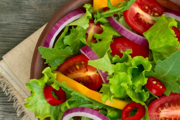 Ensalada fresca en un tazón sobre fondo de madera —  Fotos de Stock