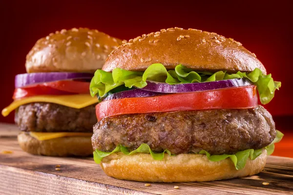 Çizburger ve hamburger ahşap ve koyu arka plan üzerinde — Stok fotoğraf