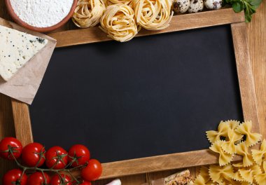 Italian food on vintage wood background with chalkboard
