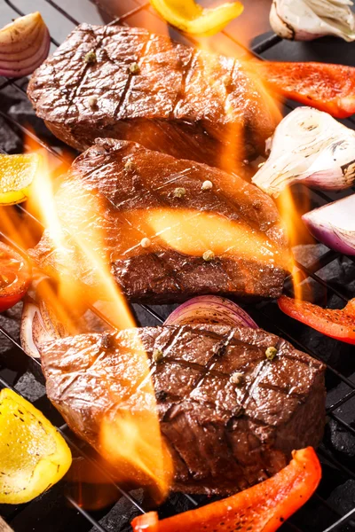 Marha steak egy barbecue grill zöldségekkel és lángok — Stock Fotó
