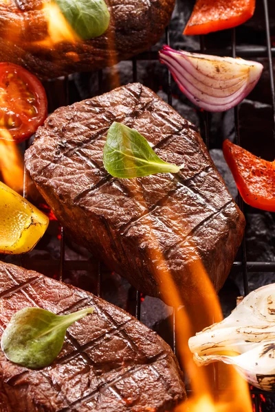 Steak de boeuf sur un barbecue avec des flammes aux légumes — Photo