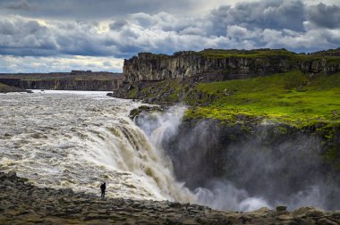 İzlanda 'daki Dettifoss şelalesinin yanında duran yürüyüşçü.