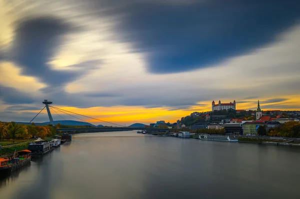 Auringonlasku Bratislavan linnan, Tonavan ja SNP-sillan yllä Slovakiassa — kuvapankkivalokuva