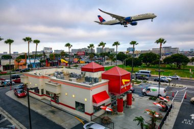 Los Angeles, Kaliforniya, ABD - 26 Mayıs 2022: Delta Airlines uçakları Los Angeles Uluslararası Havaalanı 'na inerken eski bir In-N-Out Burger restoranının üzerinde uçuyor..