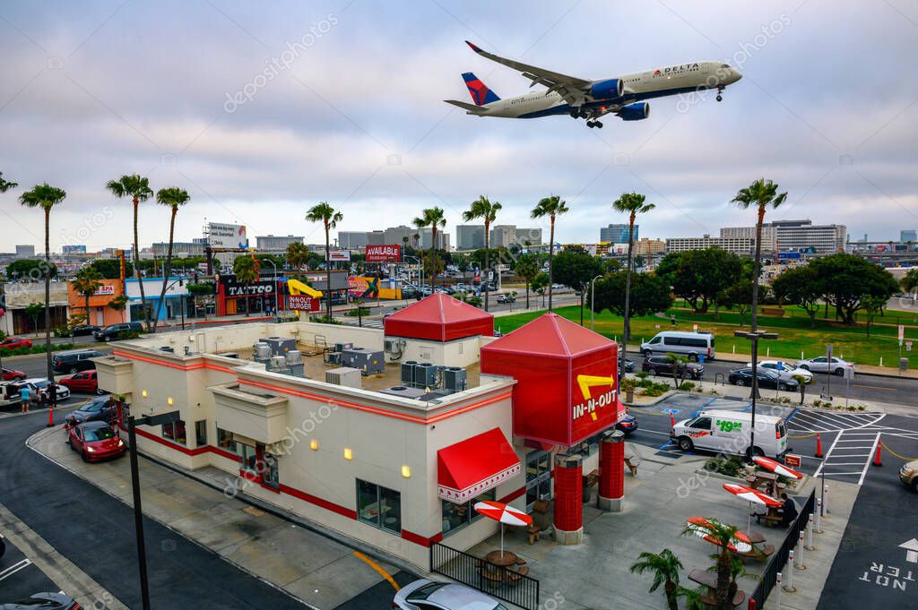 Los Angeles, California, USA - May 26, 2022 : Delta Airlines aircraft flying above a vintage In-N-Out Burger restaurant while landing at the Los Angeles International Airport LAX.