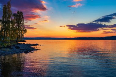 Norveç 'teki Mjosa Gölü üzerinde renkli bir günbatımı. Mjosa Norveç 'in en büyük gölü olmasının yanı sıra Norveç ve Avrupa' nın en derin göllerinden biridir..