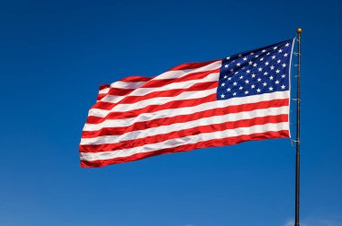 USA flag waving in the wind against a cloudless bright blue sky