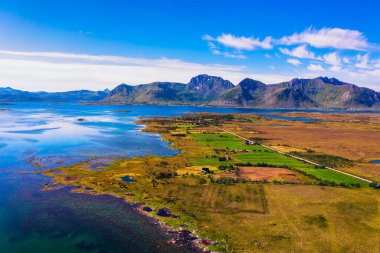 Aerial view of a road going through Lofoten Islands in Norway with mountains in the background
